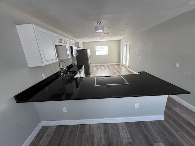 1215 Windsor Cir, Brandon, FL 33510 - kitchen featuring wood finished floors, black electric cooktop, freestanding refrigerator, a sink, and white cabinets