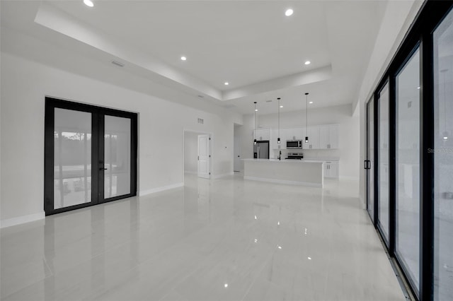 14009 Wenzel Ave, Port Charlotte, FL 33981 - unfurnished living room with a raised ceiling, recessed lighting, healthy amount of natural light, french doors, and baseboards