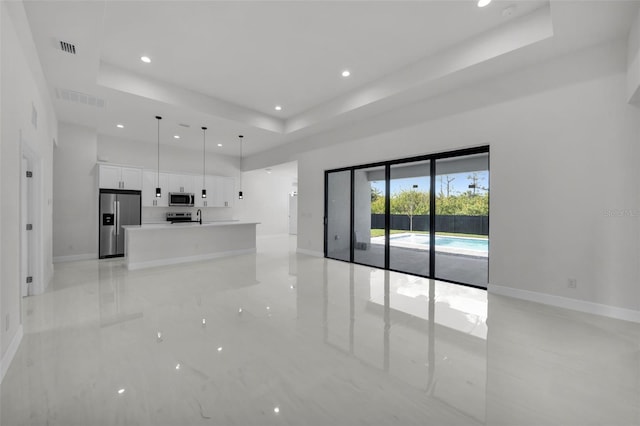 14009 Wenzel Ave, Port Charlotte, FL 33981 - unfurnished living room featuring a raised ceiling, baseboards, recessed lighting, a high ceiling, and a sink