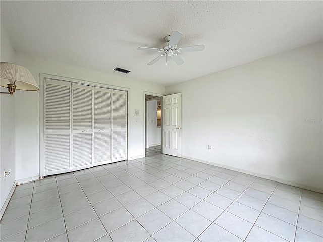 8822 Misty Creek Dr, Sarasota, FL 34241 - unfurnished bedroom with a closet, baseboards, light tile patterned floors, a textured ceiling, and a ceiling fan