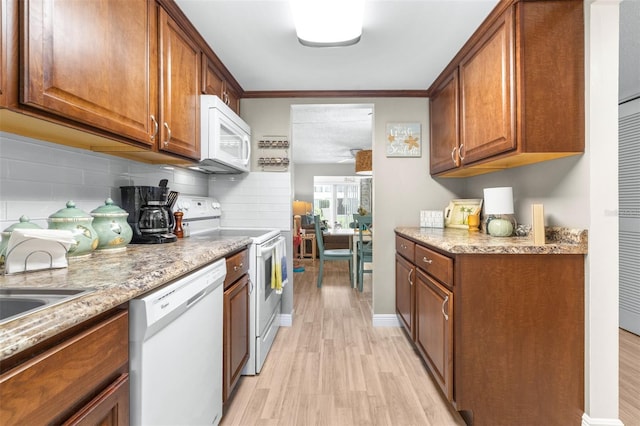 2060 Marilyn St Unit 114, Clearwater, FL 33765 - kitchen with white appliances, light wood-type flooring, brown cabinets, decorative backsplash, and ornamental molding