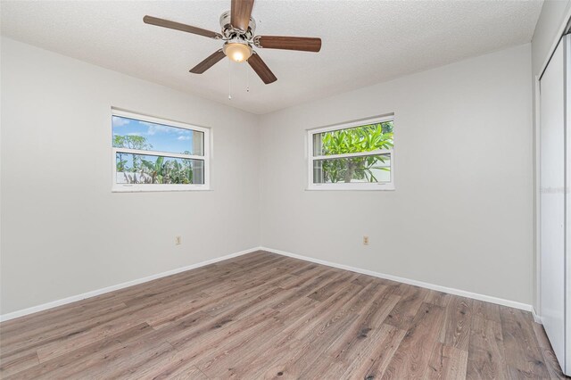1839 Neptune Dr, Englewood, FL 34223 - spare room featuring plenty of natural light, light wood finished floors, baseboards, ceiling fan, and a textured ceiling