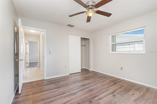 1839 Neptune Dr, Englewood, FL 34223 - unfurnished bedroom with wood finished floors, a closet, a textured ceiling, baseboards, and ceiling fan