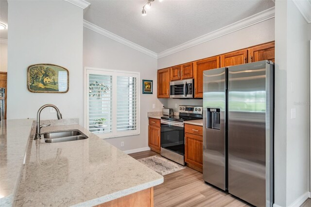 10232 Buncombe Way, San Antonio, FL 33576 - kitchen with appliances with stainless steel finishes, a sink, brown cabinetry, light wood finished floors, and vaulted ceiling