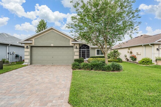 10232 Buncombe Way, San Antonio, FL 33576 - ranch-style house featuring decorative driveway, a front lawn, an attached garage, and stucco siding