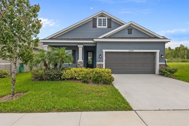 5742 Stockport St, Riverview, FL 33578 - view of front of home featuring an attached garage, stone siding, a front yard, driveway, and stucco siding