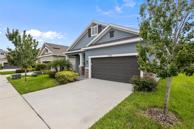 5742 Stockport St, Riverview, FL 33578 - view of front facade featuring an attached garage, a front yard, driveway, stone siding, and stucco siding
