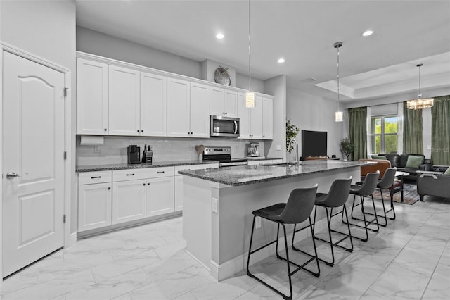 5742 Stockport St, Riverview, FL 33578 - kitchen featuring appliances with stainless steel finishes, light marble finish flooring, recessed lighting, a kitchen bar, and dark stone countertops