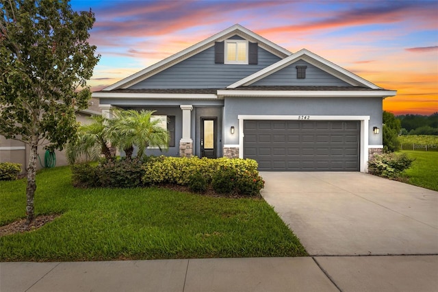 5742 Stockport St, Riverview, FL 33578 - view of front of house featuring an attached garage, concrete driveway, stone siding, a front yard, and stucco siding