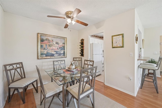 7304 W Country Club Dr N Unit 113, Sarasota, FL 34243 - dining area featuring light wood finished floors, a ceiling fan, a textured ceiling, and baseboards