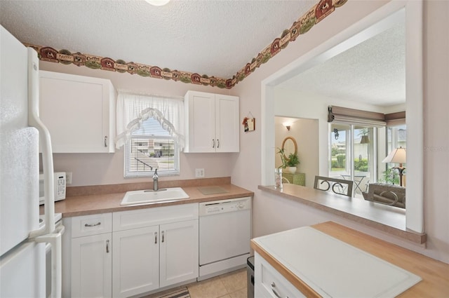 7304 W Country Club Dr N Unit 113, Sarasota, FL 34243 - kitchen with white appliances, a textured ceiling, a sink, plenty of natural light, and white cabinetry