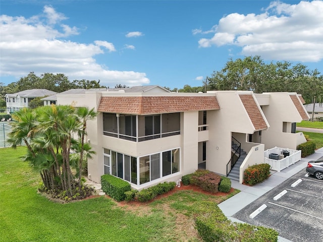 7304 W Country Club Dr N Unit 113, Sarasota, FL 34243 - back of property featuring stucco siding, uncovered parking, stairway, and a yard