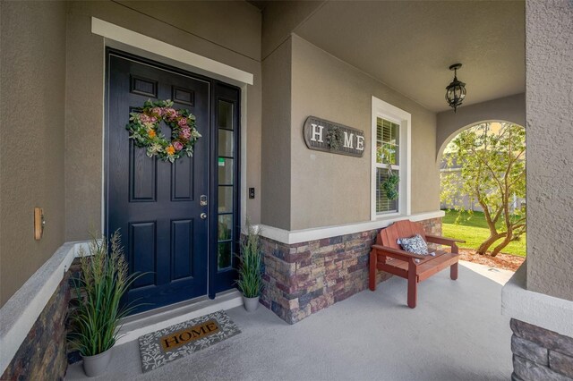 5624 Fisher Glen Loop, Wesley Chapel, FL 33545 - view of exterior entry with covered porch, stucco siding, and stone siding