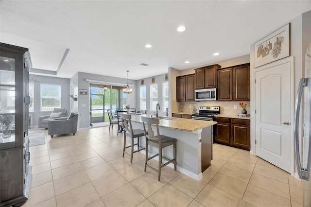 5624 Fisher Glen Loop, Wesley Chapel, FL 33545 - kitchen with appliances with stainless steel finishes, tasteful backsplash, dark brown cabinetry, a breakfast bar, and a center island with sink