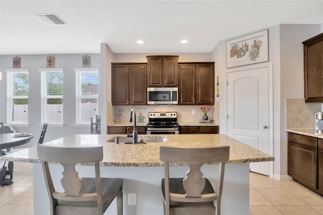 5624 Fisher Glen Loop, Wesley Chapel, FL 33545 - kitchen with stainless steel appliances, a sink, light tile patterned floors, decorative backsplash, and light stone countertops