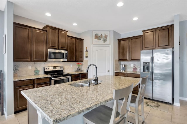 5624 Fisher Glen Loop, Wesley Chapel, FL 33545 - kitchen with stainless steel appliances, a sink, a breakfast bar, dark brown cabinets, and a center island with sink