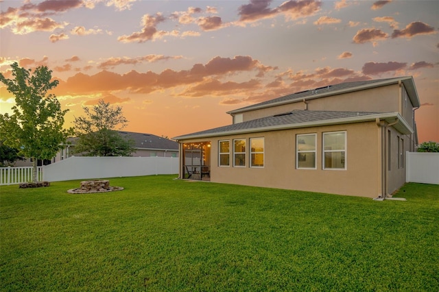 5624 Fisher Glen Loop, Wesley Chapel, FL 33545 - back of property at dusk featuring stucco siding, a fire pit, and a sunroom