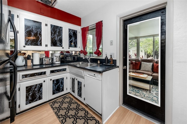 614 12th St NW, Largo, FL 33770 - kitchen featuring light wood-style floors, dark countertops, white dishwasher, and white cabinetry
