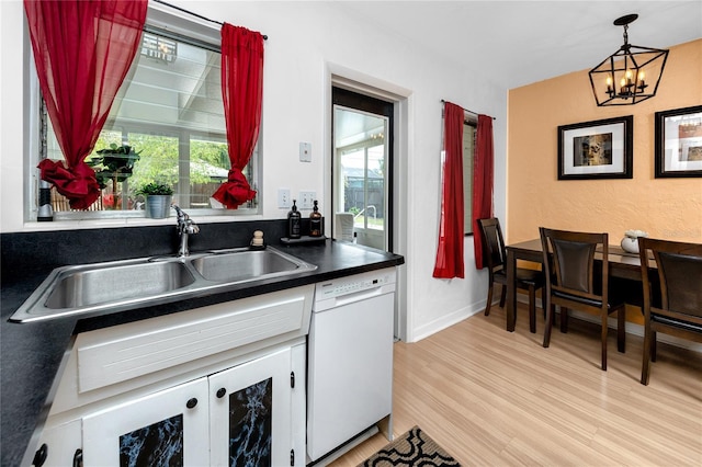 614 12th St NW, Largo, FL 33770 - kitchen with white dishwasher, dark countertops, light wood-style flooring, a chandelier, and white cabinets