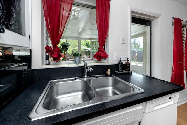 614 12th St NW, Largo, FL 33770 - kitchen with dishwasher, white cabinetry, black microwave, and dark countertops