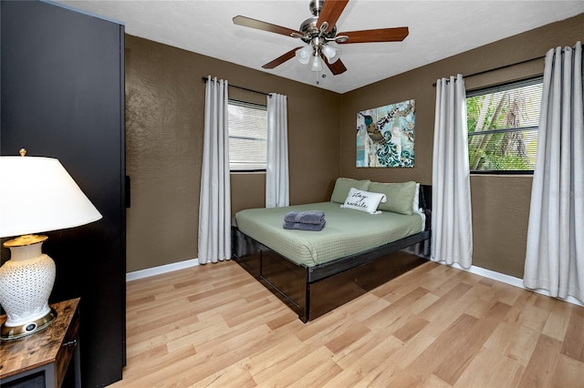 614 12th St NW, Largo, FL 33770 - bedroom with light wood finished floors, multiple windows, a textured wall, and a ceiling fan