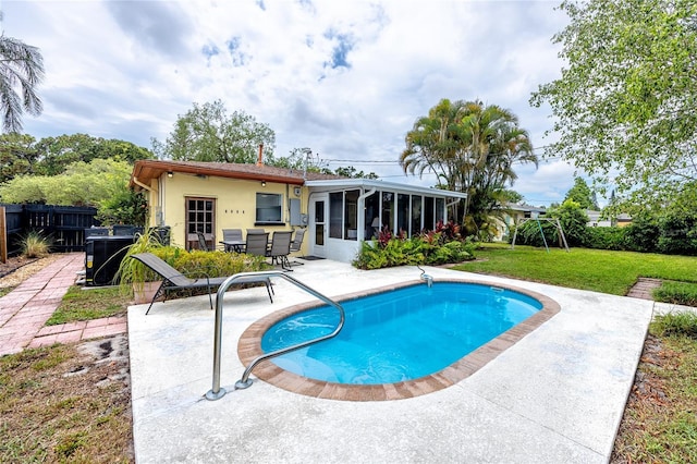 614 12th St NW, Largo, FL 33770 - back of property featuring a sunroom, a patio area, an outdoor pool, and stucco siding