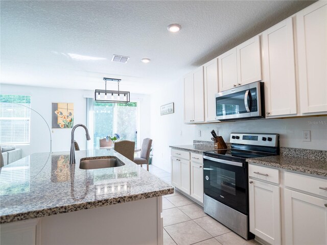 573 Vista Villages Blvd, Davenport, FL 33896 - kitchen featuring appliances with stainless steel finishes, a sink, white cabinetry, light tile patterned floors, and light stone countertops