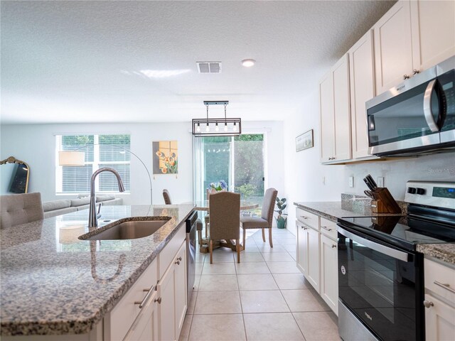 573 Vista Villages Blvd, Davenport, FL 33896 - kitchen featuring stainless steel appliances, a sink, white cabinetry, light tile patterned flooring, and light stone counters