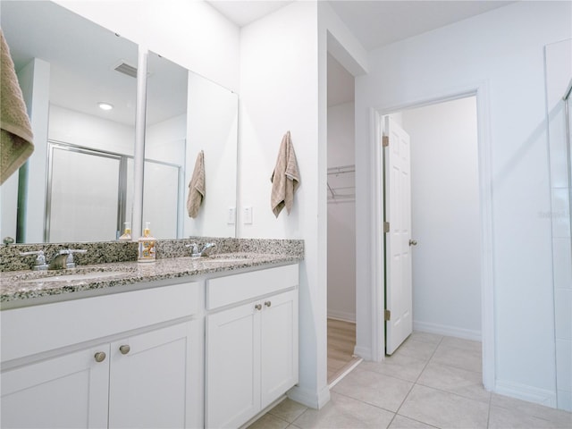 573 Vista Villages Blvd, Davenport, FL 33896 - bathroom with a shower stall, double vanity, a walk in closet, baseboards, and tile patterned flooring