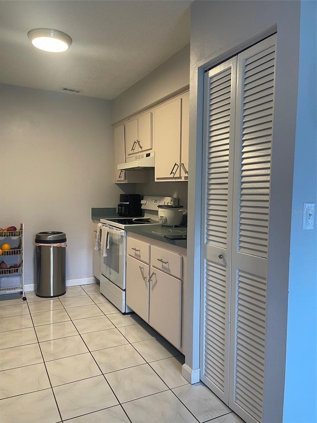 3802 Cortez Cir Unit D, Tampa, FL 33614 - kitchen featuring white range with electric stovetop, under cabinet range hood, dark countertops, white cabinets, and light tile patterned flooring