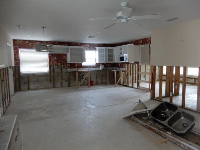 1897 Dolphin Blvd S, Saint Petersburg, FL 33707 - kitchen with white microwave, white cabinetry, and a ceiling fan