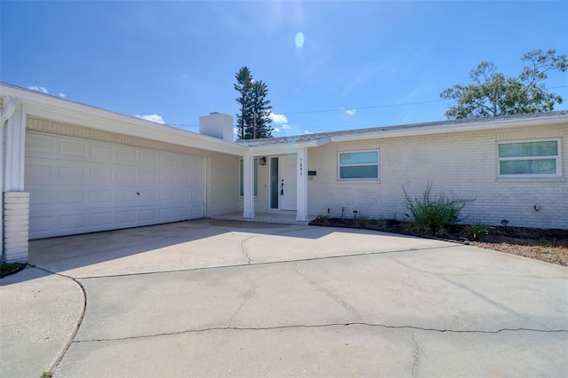 1897 Dolphin Blvd S, Saint Petersburg, FL 33707 - view of front facade with a chimney, concrete driveway, brick siding, and an attached garage