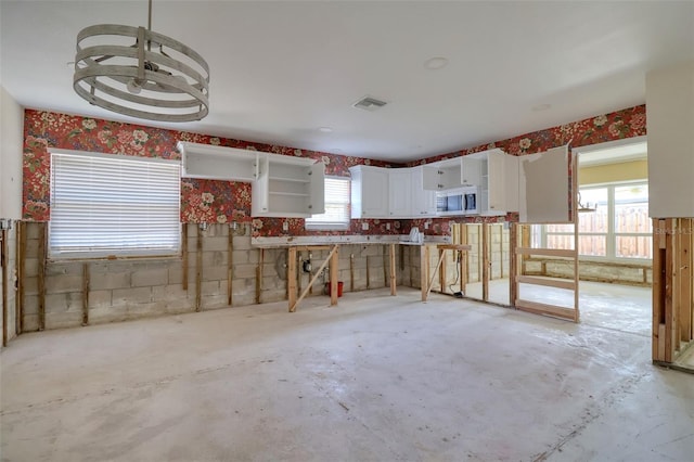 1897 Dolphin Blvd S, Saint Petersburg, FL 33707 - kitchen featuring stainless steel microwave, concrete flooring, white cabinetry, and open shelves