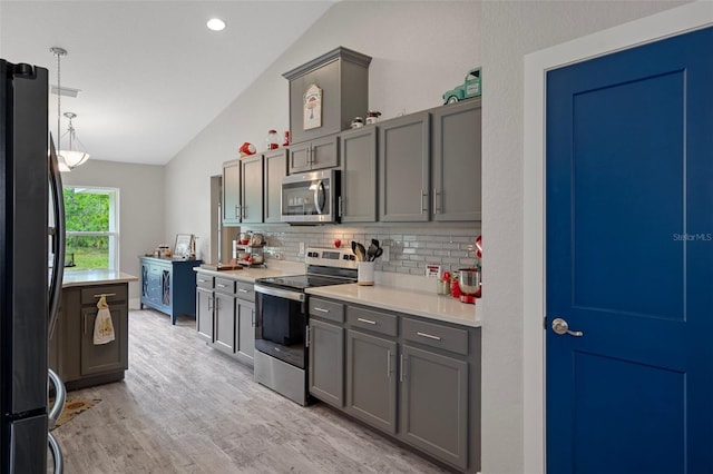 16473 Scaup Duck Ave, Weeki Wachee, FL 34614 - kitchen with appliances with stainless steel finishes, vaulted ceiling, decorative backsplash, light wood finished floors, and light countertops
