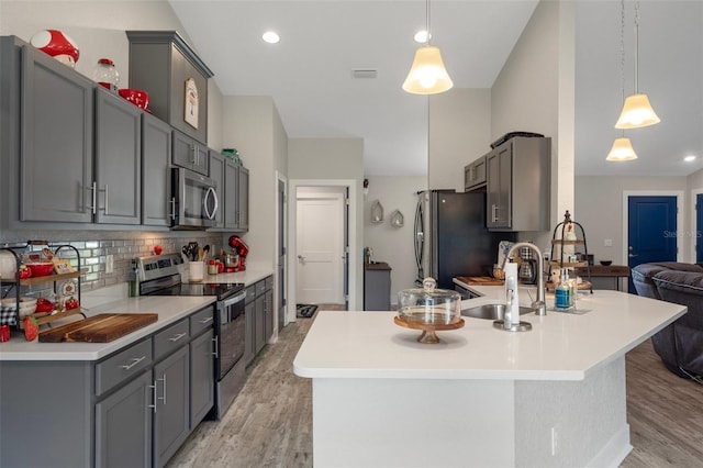 16473 Scaup Duck Ave, Weeki Wachee, FL 34614 - kitchen featuring stainless steel appliances, light wood finished floors, gray cabinetry, decorative backsplash, and light countertops