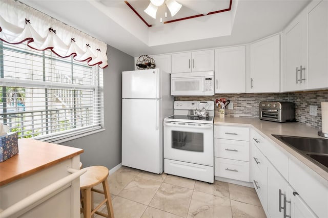 960 Virginia St Unit 202, Dunedin, FL 34698 - kitchen featuring white appliances, a raised ceiling, backsplash, ceiling fan, and white cabinetry