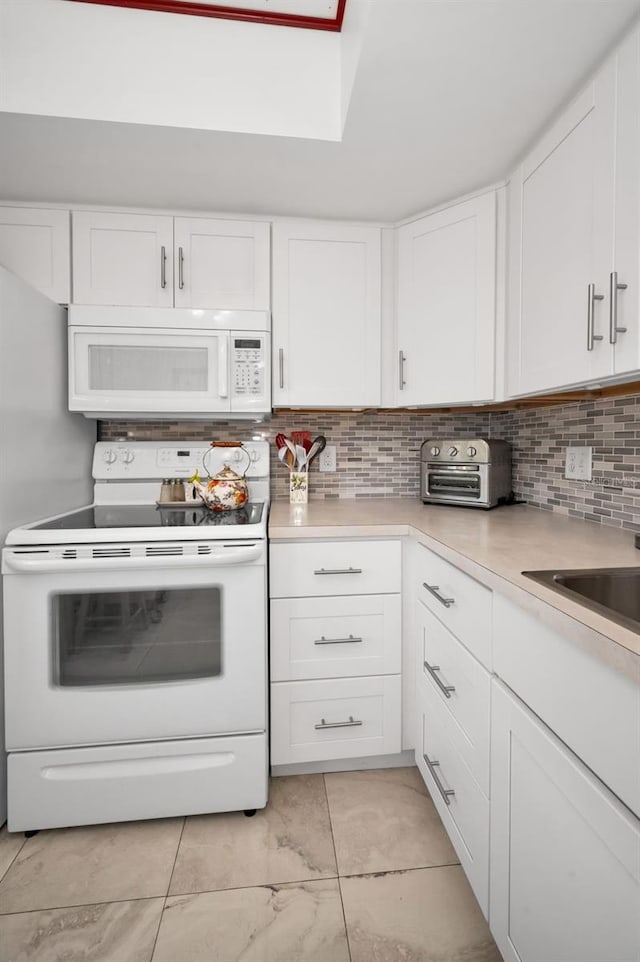 960 Virginia St Unit 202, Dunedin, FL 34698 - kitchen featuring white appliances, tasteful backsplash, white cabinetry, light countertops, and a skylight