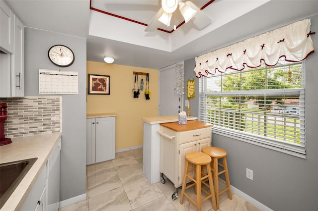 960 Virginia St Unit 202, Dunedin, FL 34698 - kitchen with light marble finish floors, light countertops, ceiling fan, tasteful backsplash, and white cabinetry