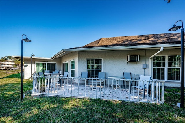 960 Virginia St Unit 202, Dunedin, FL 34698 - rear view of house with stucco siding, a patio, a yard, roof with shingles, and outdoor dining area