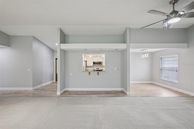 3121 Egret Ter, Safety Harbor, FL 34695 - unfurnished living room featuring light colored carpet, baseboards, a ceiling fan, a sink, and light wood-type flooring