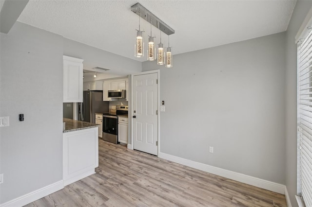 3121 Egret Ter, Safety Harbor, FL 34695 - kitchen with appliances with stainless steel finishes, white cabinetry, light wood finished floors, baseboards, and dark stone countertops