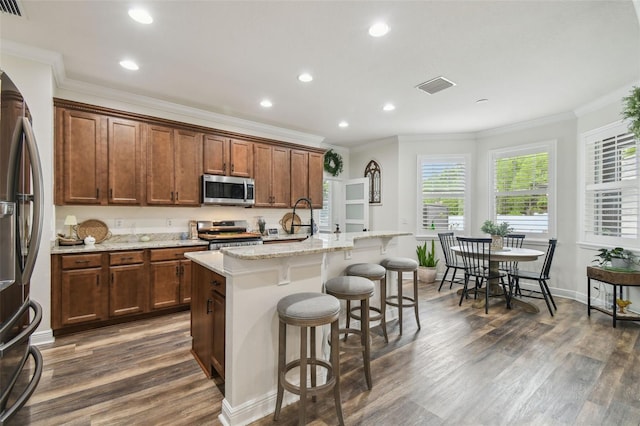 10422 Fenceline Rd, New Port Richey, FL 34655 - kitchen with appliances with stainless steel finishes, dark wood-type flooring, crown molding, a breakfast bar, and recessed lighting