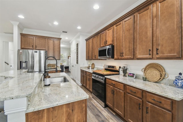 10422 Fenceline Rd, New Port Richey, FL 34655 - kitchen with stainless steel appliances, a sink, crown molding, a center island with sink, and light stone counters