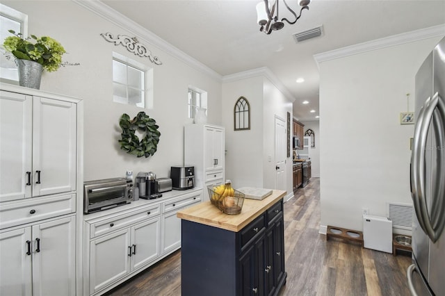 10422 Fenceline Rd, New Port Richey, FL 34655 - kitchen with butcher block countertops, freestanding refrigerator, dark wood-type flooring, ornamental molding, and white cabinetry
