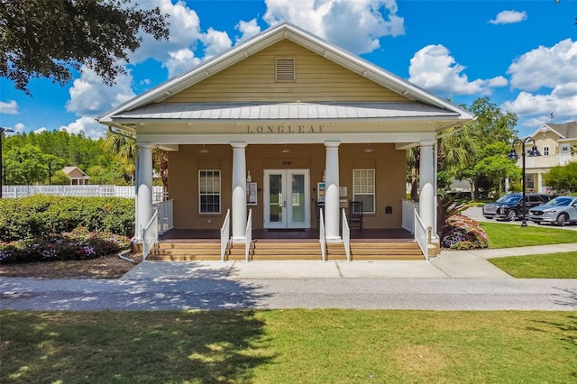 10422 Fenceline Rd, New Port Richey, FL 34655 - greek revival inspired property featuring covered porch, french doors, stucco siding, and metal roof
