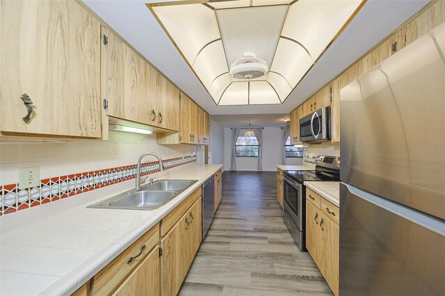 1508 Ingram Dr Unit 20, Sun City Center, FL 33573 - kitchen with stainless steel appliances, a sink, tile countertops, backsplash, and light wood finished floors