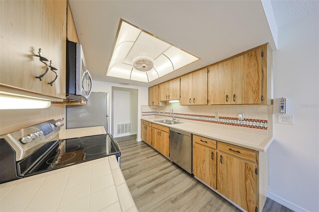 1508 Ingram Dr Unit 20, Sun City Center, FL 33573 - kitchen featuring stainless steel appliances, tile counters, light wood finished floors, and tasteful backsplash