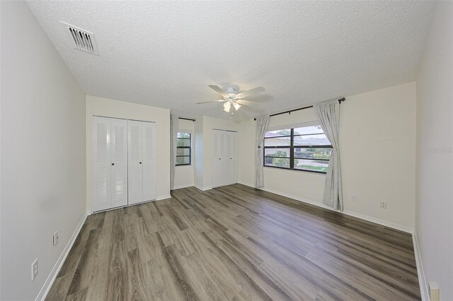 1508 Ingram Dr Unit 20, Sun City Center, FL 33573 - unfurnished bedroom featuring two closets, wood finished floors, a textured ceiling, baseboards, and ceiling fan