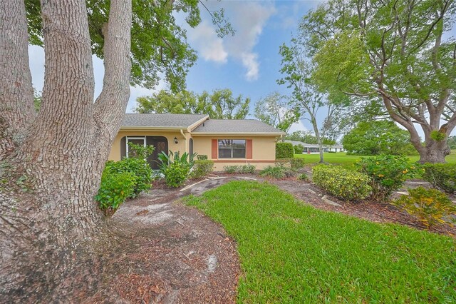 1508 Ingram Dr Unit 20, Sun City Center, FL 33573 - view of front of house featuring stucco siding, a front yard, and a shingled roof