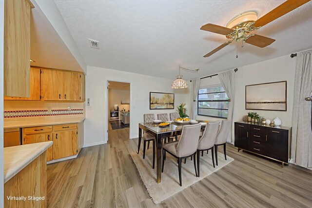 1508 Ingram Dr Unit 20, Sun City Center, FL 33573 - dining area with light wood finished floors, ceiling fan, a chandelier, baseboards, and a textured ceiling